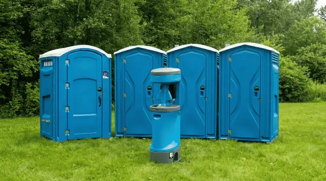 Four blue portable toilets and a matching hand washing station on grass near trees, a common sight at local outdoor events in Tallahassee, FL